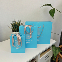 Vente en gros de sacs à provisions de cadeaux en papier bleu ruban de luxe avec impression offset de logo argenté personnalisé pour l'emballage de bougies