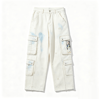 Jean cargo blanc à jambe large, délavé effet éclaboussures de peinture bleue, avec bords de poche effilochés, détails déchirés, décorations patchwork, coupe ample, style streetwear en denim