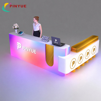 Comptoir d'accueil moderne éclairé bleu et blanc avec logo LED à effet ondulé superposé, comptoir spacieux et fabrication OEM professionnelle pour entreprises