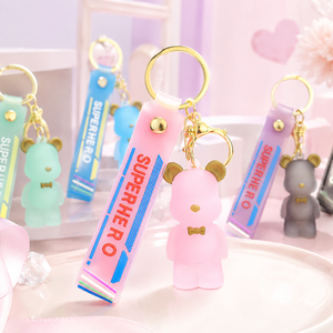 Prêt à expédier : Magnifique porte-clés en PVC ours 3D givré avec oreilles dorées, nœud papillon et bracelet SUPERHERO - Product Image 1
