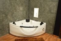 Baignoire d'angle moderne avec jets de massage et façade transparente