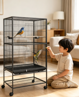 Grande volière en métal noir avec base à roulettes, étagère de rangement et nombreuses perchoirs en bois pour accueillir de nombreux perroquets de taille moyenne