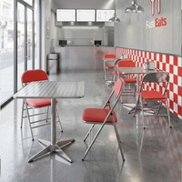 Ensemble table et chaises de style industriel pour restaurant de restauration rapide, comprenant une table réfléchissante et des chaises rembourrées et pliables.