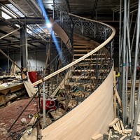 Escalier en colimaçon courbé sur mesure, garde-corps en fer forgé orné, marches en bois, design luxueux pour villa, hôtel, grand hall intérieur