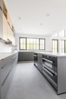 Meubles de cuisine modernes bicolores sur mesure, anthracite et chêne clair, sans poignées, avec îlot large et étagères LED, pour projet résidentiel
