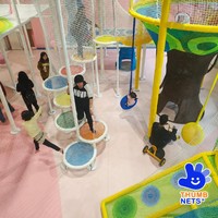 Structure de grimpette intérieure multi-niveaux en filet blanc avec poteaux rembourrés et plateformes colorées – Équipement commercial pour centre de jeux pour enfants