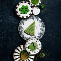 Ensemble d'assiettes en porcelaine avec feuilles tropicales, rayures radiales noires et blanches et motifs géométriques avec accents dorés
