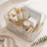 Panier de rangement transparent haut de gamme avec poignées dorées et design empilable pour maquillage, cosmétiques et articles de toilette