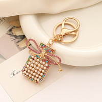 Porte-clés pendentif exquis en métal avec nœud, pompon, perle et flacon de parfum, petit cadeau