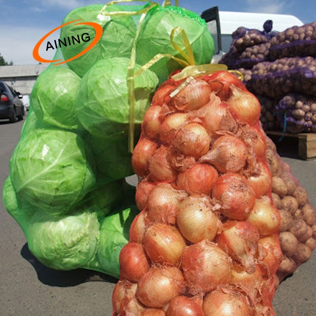 Collected onions in orange mesh bags on the field ecofriendly fresh vegetables are harvested for sale