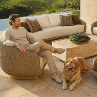 Ensemble de canapés en rotin de luxe pour l'extérieur avec coussins crème, chaises longues et ottomanes arrondies imperméables pour usage hôtelier
