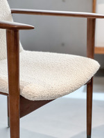 Chaise de restaurant haut de gamme en bois d'frêne massif, avec accoudoirs coniques architecturaux, revêtement en bouclette texturée et finition peinte.