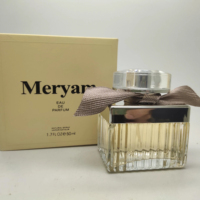 Parfum féminin en verre côtelé carré avec capuchon argenté, ruban taupe, boîte crème, senteur fleurie chaude, tenue longue durée, idéal pour les rendez-vous