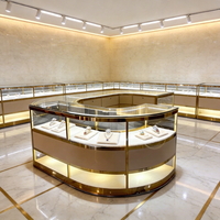 Ensemble de présentoirs de bijouterie moderne avec cadre doré, écoresponsable, éclairage LED, îlot central incurvé et vitrines périmétriques pour la vente au détail de luxe