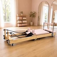 Machine de Pilates Reformer en bois avec coussin rose pour entraînement du tronc, étirements et entraînement complet du corps à domicile ou en studio