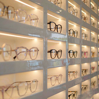 Système d'affichage mural pour lunettes en laque blanche avec étagères LED lumineuses et comptoir à tiroirs pour l'aménagement de magasins d'optique