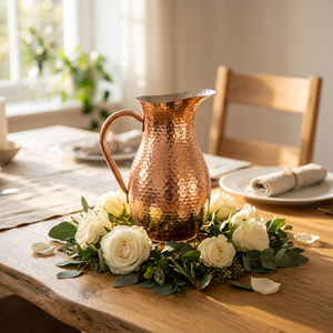 Pichet en cuivre martelé vintage avec centre de table orné de roses blanches et de verdure pour la décoration de table de mariage - Product Image 1