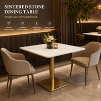 Table et chaises de restaurant, plateau carré en pierre frittée avec base cylindrique dorée et fauteuils beiges à accoudoirs en forme de baril pour café-bar