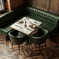 Ensemble de mobilier moderne pour café-restaurant : Table et chaises en pierre frittée verte, banquette en cuir vert en forme de L, et canapé banquette.
