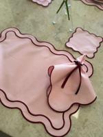 Set aus rosa Tischsets mit gewelltem Rand und burgunderroten Stoffservietten und Untersetzer, elegante Tischdekoration, kokettes Essensset