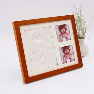 Un marco de fotos de madera maciza con tinta para manos y pies que registra el crecimiento de un bebé Centenario en una caja de regalo
