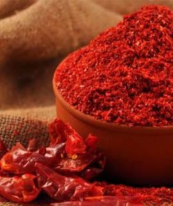 Poudre de piment rouge dans un bol en argile avec des piments séchés à côté - Product Image 6