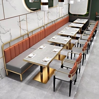Banquette de restaurant confortable et légère en cuir gris à dossier haut, base de table basse dorée et chaise de restaurant blanche