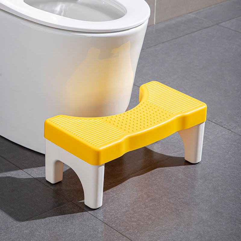 Le tabouret a une surface grise et des pieds blancs.
