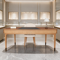 Bureau VIP en bois courbé de luxe avec pieds coniques et embouts en bronze, chaise Boucle, niche murale LED, aménagement boutique, table de réception