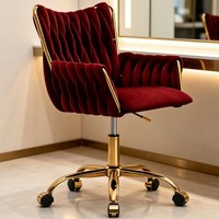 Fauteuil de détente en velours rouge, dossier haut capitonné, hauteur réglable, base pivotante en métal doré, roulettes
