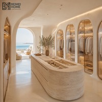 Dressing sur mesure de style cycladique avec armoires en verre cannelé et îlot en travertin brut, suite de dressing pour villa
