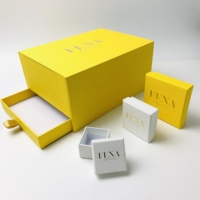 Boîte cadeau pour bijoux A1 gaufrée blanche avec zone de texte dorée, sac jaune et surface tactile pour la remise aux clients de marques de boutiques