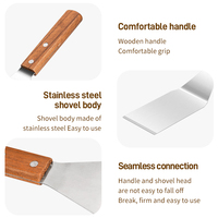 Ensemble d'ustensiles de cuisine en acier inoxydable gris avec manche en bois : spatule, pelle, poêle à frire, plaque à pizza et plaque de cuisson anti-goutte