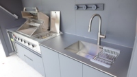Cuisine extérieure moderne tout-en-un en acier inoxydable avec îlot barbecue, réfrigérateur, évier, rangement et éclairage de plafond