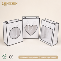 Sacs cadeaux en papier blanc personnalisés OEM avec fenêtre (cercle, cœur, carré) et poignées torsadées pour boutiques