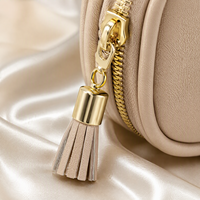 Étui de voyage beige pour bijoux avec fermeture éclair, anneau de traction à pompon et poche intérieure
