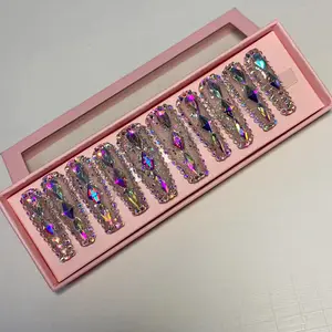 Hand-pressed fingernails blend colors in a variety of shapes with a shimmering Rhinestone all over the wearable nails