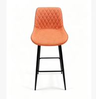 Tabouret de bar en cuir orange matelassé avec dossier en losanges, quatre pieds en métal noir, repose-pieds, hauteur de comptoir
