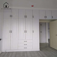 Armoire blanche sur mesure XINGRUO avec portes à panneaux surélevés, poignées noires, tiroirs et rangement pleine hauteur
