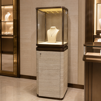 Vitrine à bijoux verrouillable en verre transparent avec finition bronze, éclairage LED intégré et base de rangement aspect pierre pour salles d'exposition de bijoux de luxe