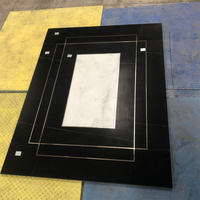 Ascenseur de luxe avec motifs gravés au jet d'eau sur marbre noir Marquina et blanc, et bandes en cuivre et laiton intégrées