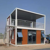 Maison conteneur préfabriquée à double étage avec structure blanche, modules décalés, mur en verre et terrasse sur le toit pour bureau moderne