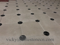 Carrelage de sol en pierre calcaire beige avec points noirs en forme d'échiquier