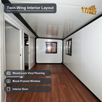 Villa de luxe moderne en conteneur extensible de 20 pieds, à double ailes, avec cadre noir et panneaux muraux blancs, deux chambres et un appartement