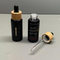 Vente en gros de flacons compte-gouttes en verre noir brillant de 30 ml avec compte-gouttes en bambou et impression sérigraphique pour les gouttes pour les yeux et les sérums pour le soin de la peau