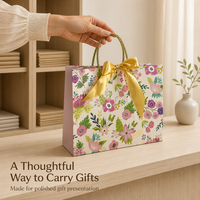 Sac cadeau en papier imprimé floral avec nœud en satin doré et poignées en corde torsadée pour l'emballage de cadeaux de détail