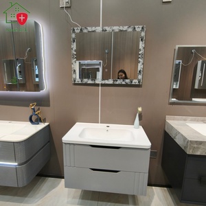 Mueble de baño gris con diseño de doble cajón, espejo con marco de encaje, encimera blanca redondeada y lavabo blanco - Product Image 1