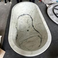 Baignoire autoportante ovale en marbre blanc avec rebord large et base sculpturale pour villas et hôtels