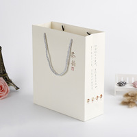 Sac en papier blanc imprimé personnalisé avec logo noir Sac cadeau recyclable pour vêtement de luxe avec poignée en corde pour chaussures