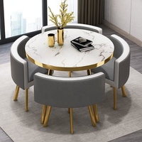 Ensemble de table à manger ronde de luxe en métal doré avec quatre chaises rembourrées, plateau de table aspect marbre et finition dorée stable
